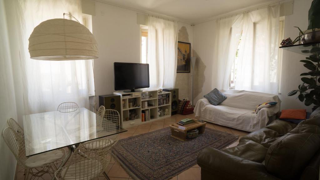 een woonkamer met een bank en een tv bij Appartamento moderno a 2 passi dal Duomo di Parma in Parma