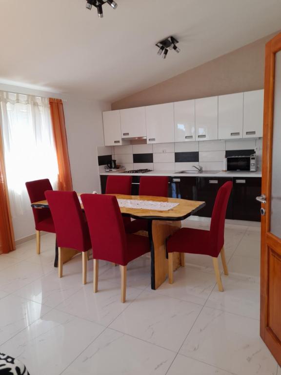 a kitchen with a wooden table and red chairs at loren in Pirovac