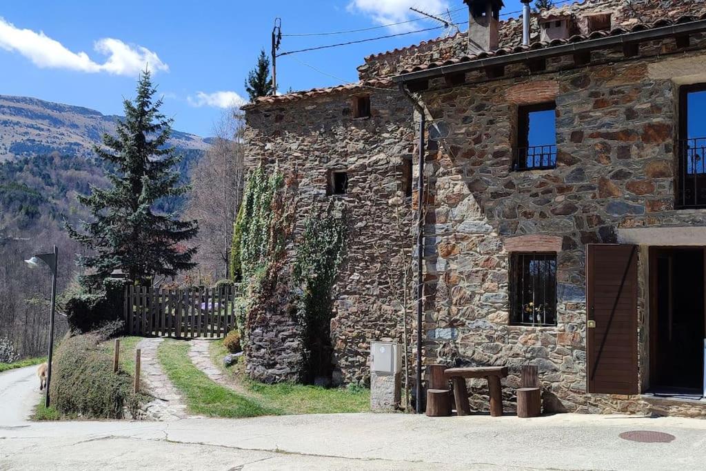 un bâtiment en pierre avec une clôture à côté d'une rue dans l'établissement Casa Rural con Jacuzzi junto a Camprodon., à Abella