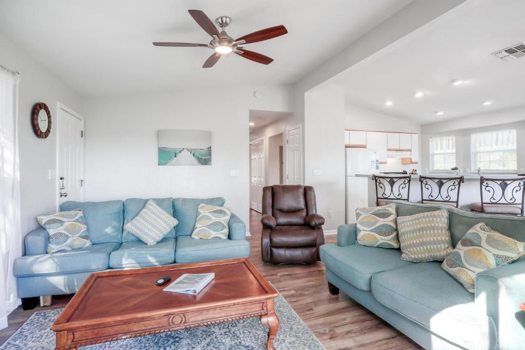 uma sala de estar com sofás azuis e uma ventoinha de tecto em Sunrise Cottage em Saint Augustine
