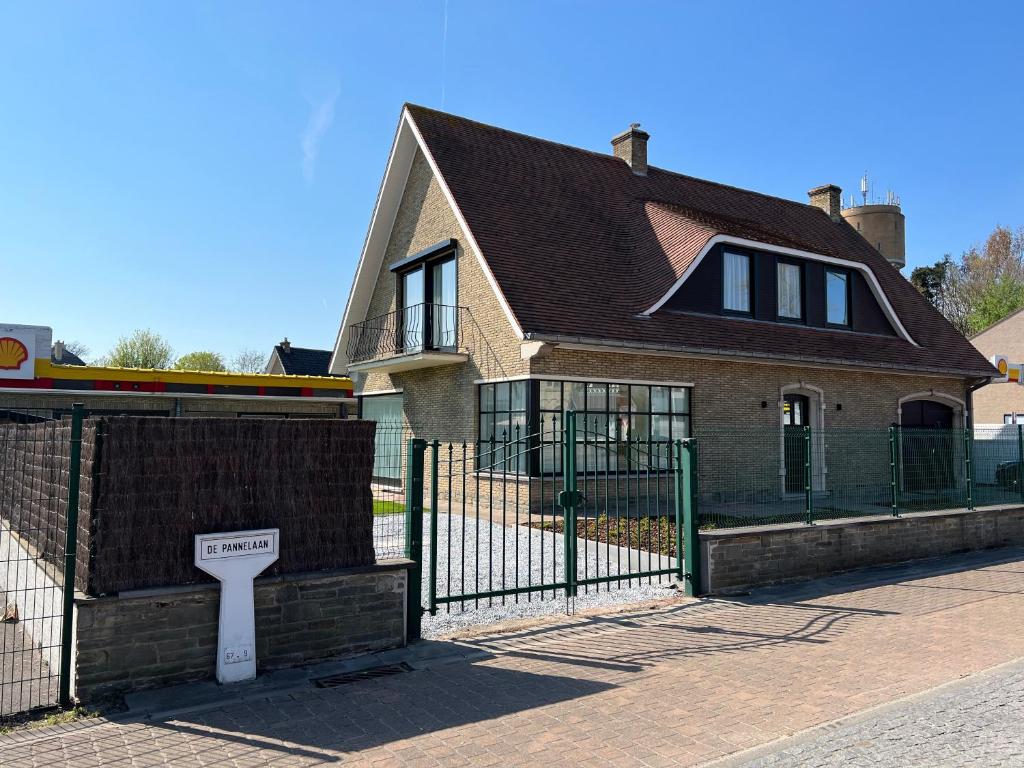 a house with a sign in front of a fence at villa dunepanne in Adinkerke