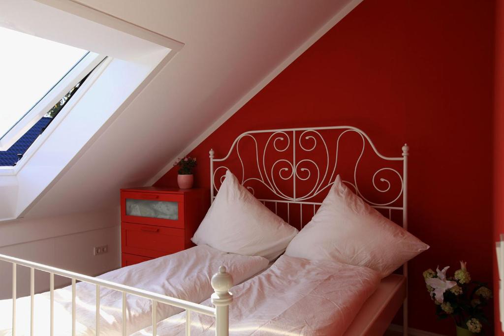 ein Schlafzimmer mit einem Bett mit einer roten Wand in der Unterkunft Messezimmer Hannover / Private rooms for exhibitions in Hannover