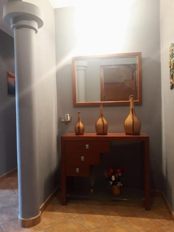 a mirror and three vases on a dresser in a room at O DESCANSO DE MANDUCA in Mazaricos