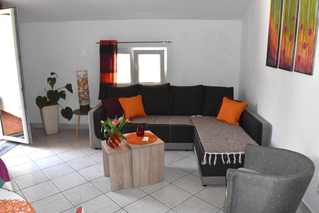 - un salon avec un canapé noir et des oreillers orange dans l'établissement Apartment Iris, à Kotor