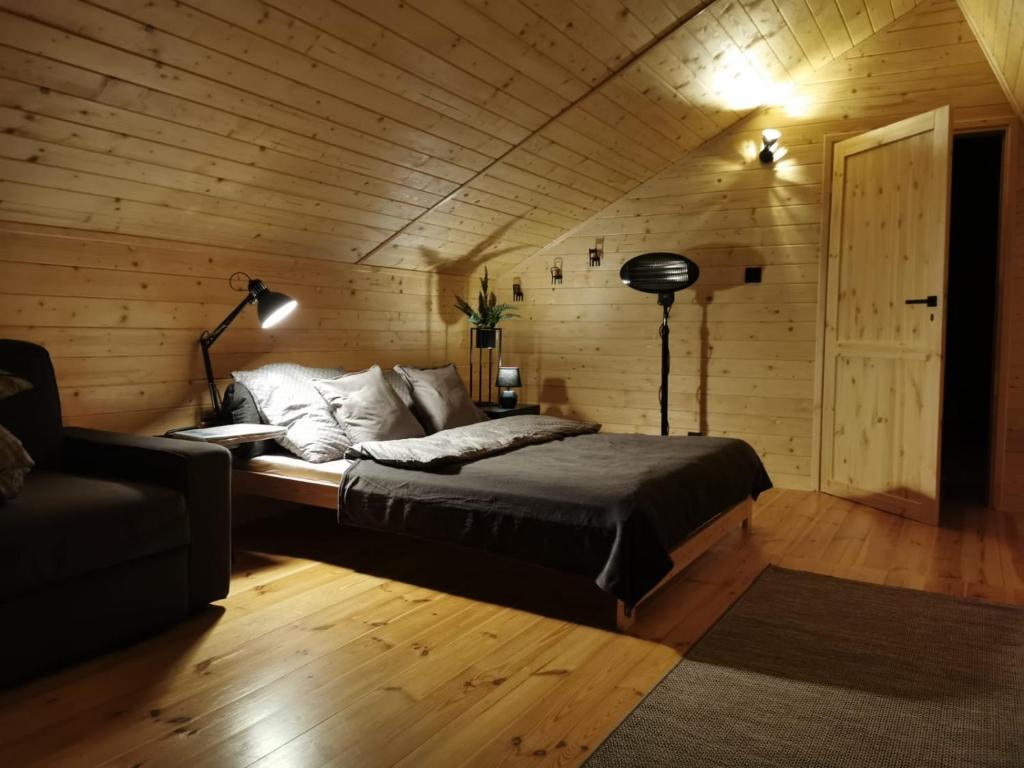 1 dormitorio con 1 cama en una pared de madera en Na Zakręcie - Domek Loft, en Błędowo