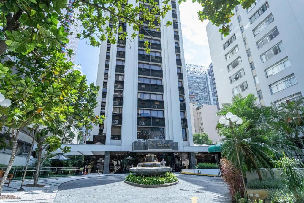 a tall building with a fountain in front of it at Apartamentos & Flats La Residence Paulista in São Paulo