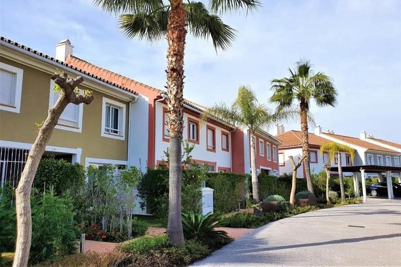 een rij palmbomen voor een gebouw bij Lovely 3-bedroom townhouse with shared pool in Estepona