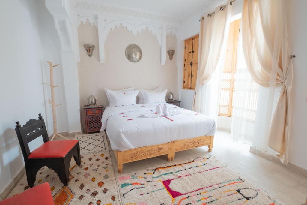 1 dormitorio con 1 cama blanca y 1 silla roja en Riad El Habib, en Marrakech