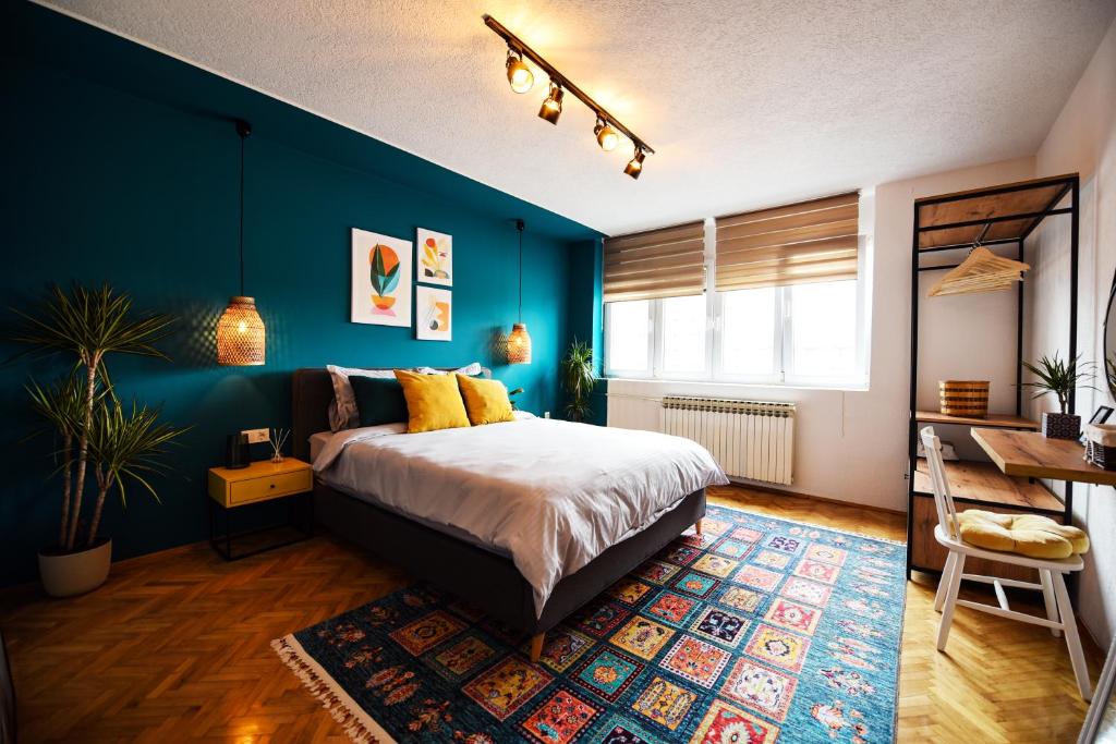 een slaapkamer met een bed en een blauwe muur bij Cozy Bright Central in Pristina