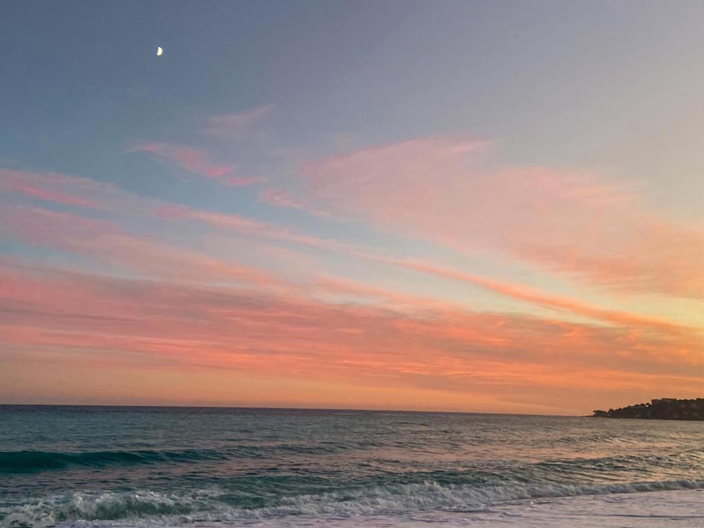- un coucher de soleil sur la plage avec l'océan dans l'établissement Calme et Plages, à Menton
