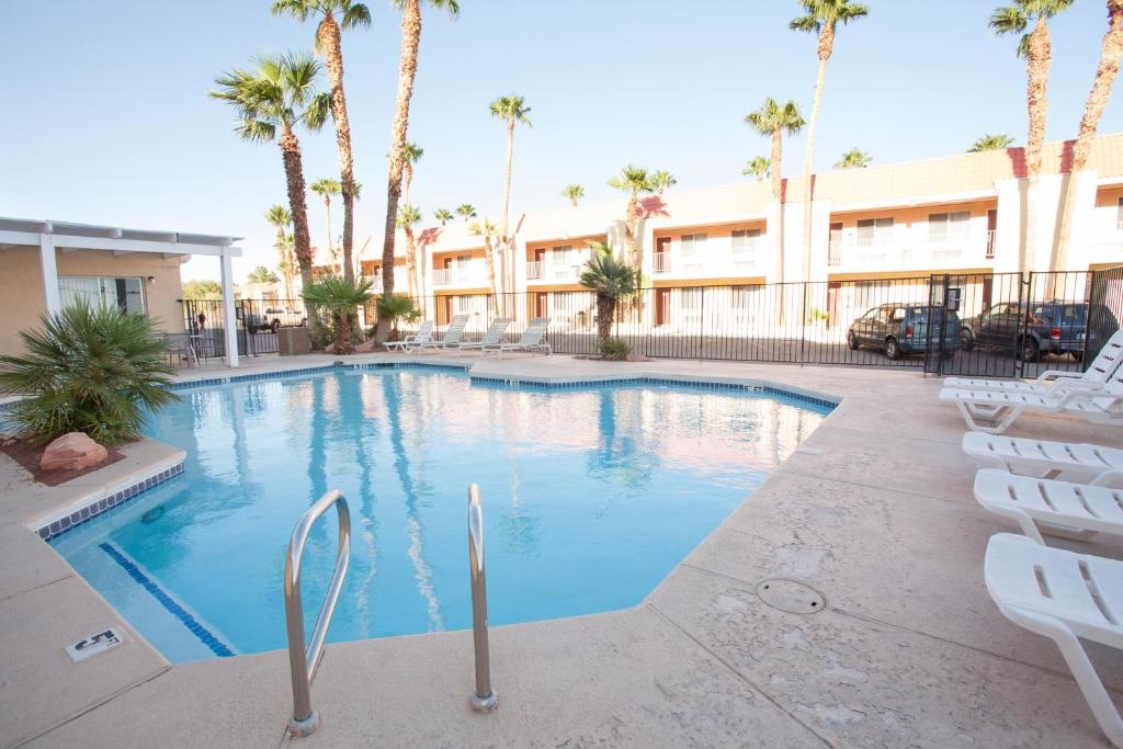 a large swimming pool with chairs and palm trees at Aviation Inn in Las Vegas