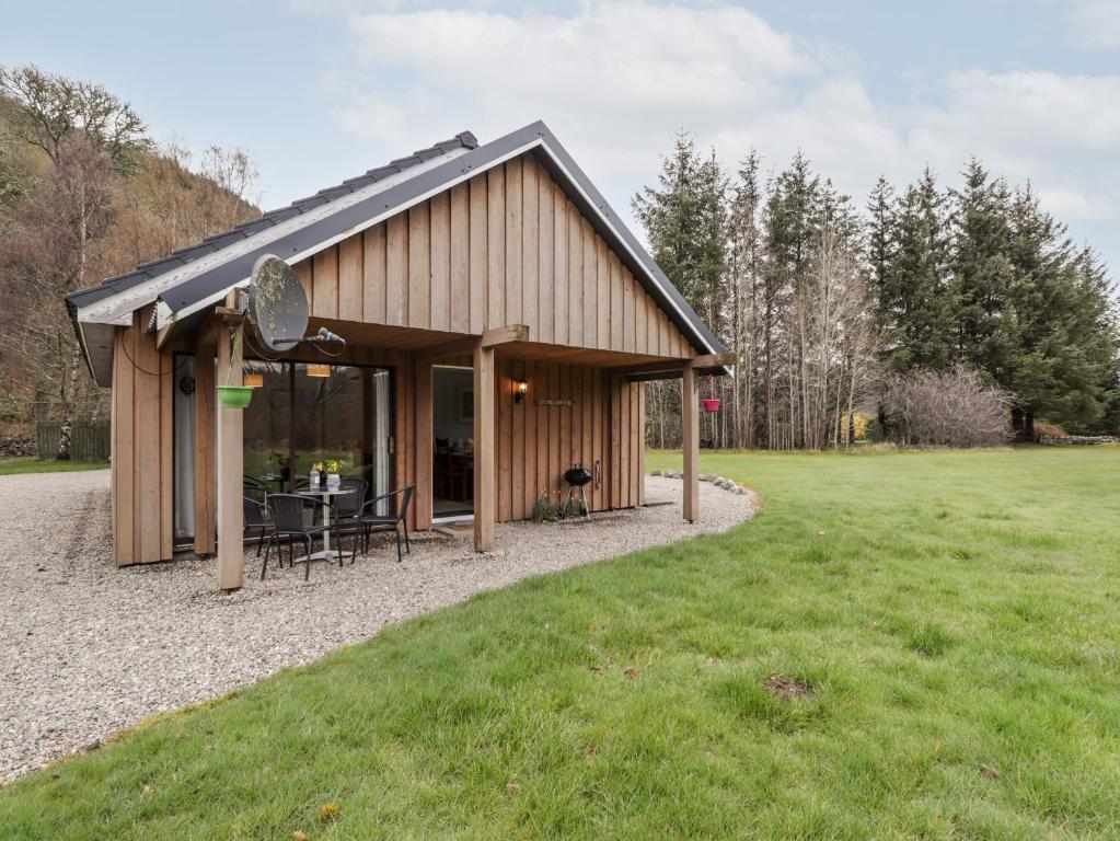 a building with a table and chairs in a field at Stone Water Cottage in Contin