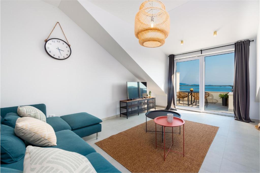 a living room with a blue couch and a clock at Divine Apartment in Mlini