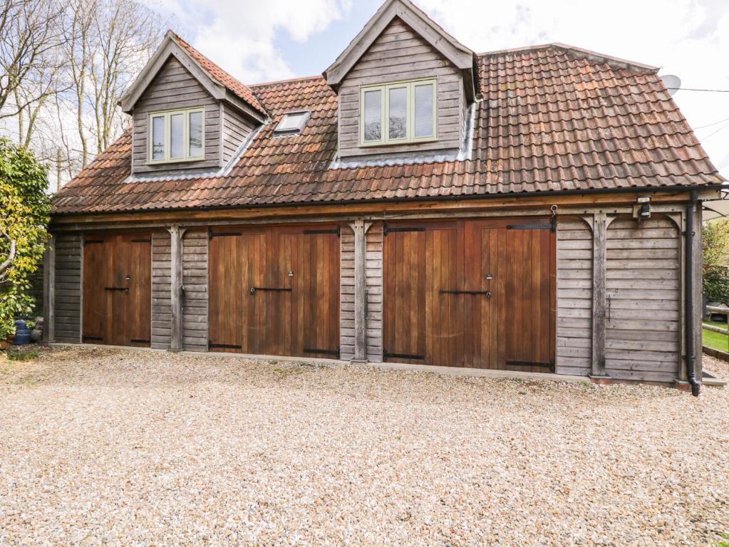 a house with wooden garage doors on a gravel driveway at Shephards Retreat in Kingsdon