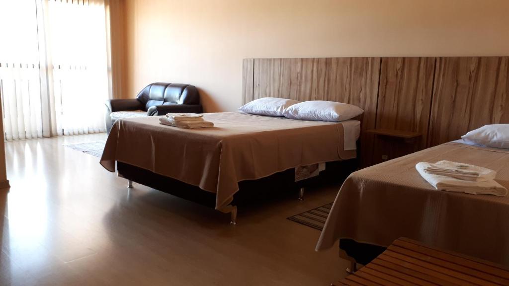 um quarto de hotel com duas camas e uma cadeira em Hotel Dona Marta em Maria da Fé