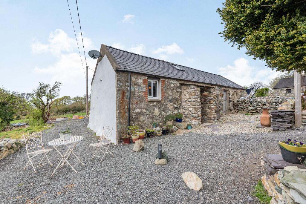 een stenen huisje met een tafel en stoelen ervoor bij Celyn Farm Cottage in Cwm-y-glo