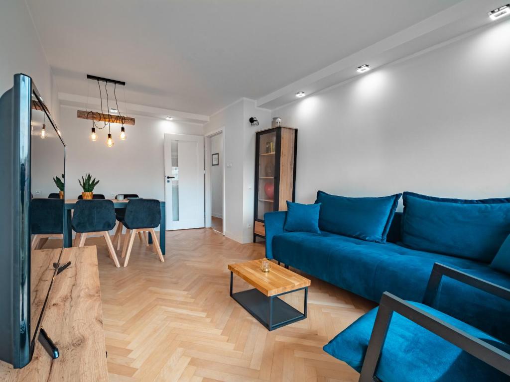- un salon avec un canapé bleu et une table dans l'établissement Apartament Bursztynowy Nowy, à Sopot