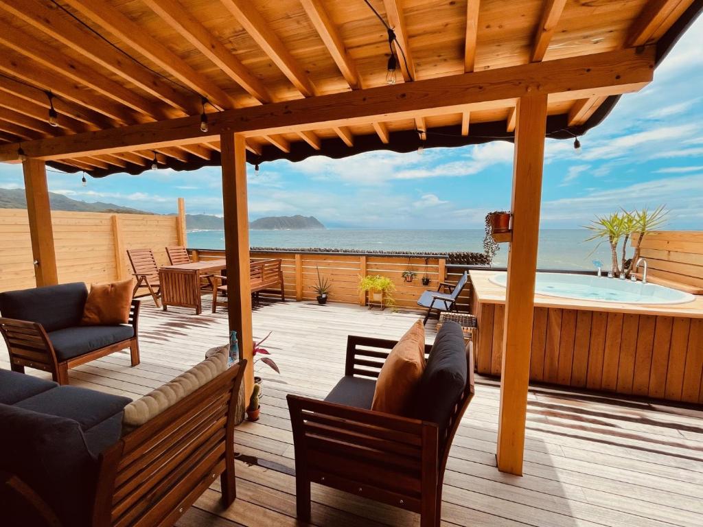 una terraza de madera con bañera de hidromasaje en un patio en PACIFICO SURF HOUSE - by the Sea en Shishikui