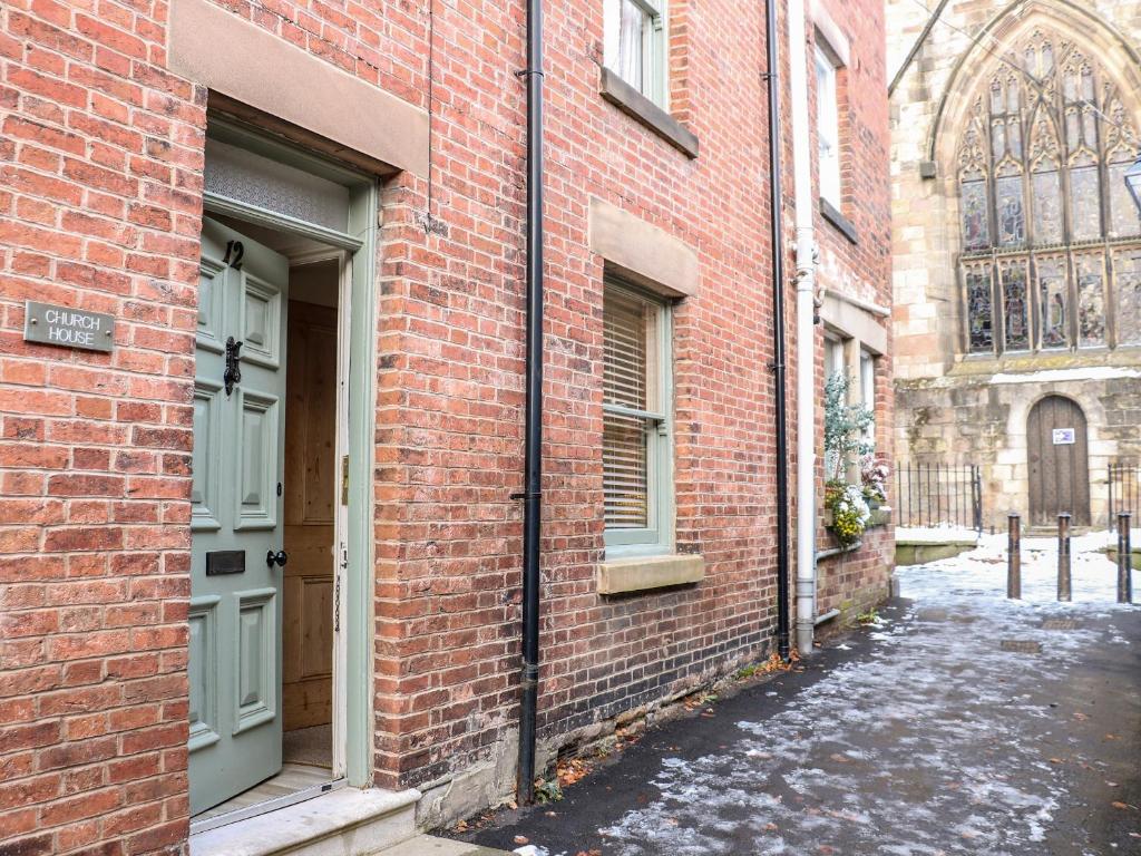 an alley with a brick building with a door at Church House in Matlock