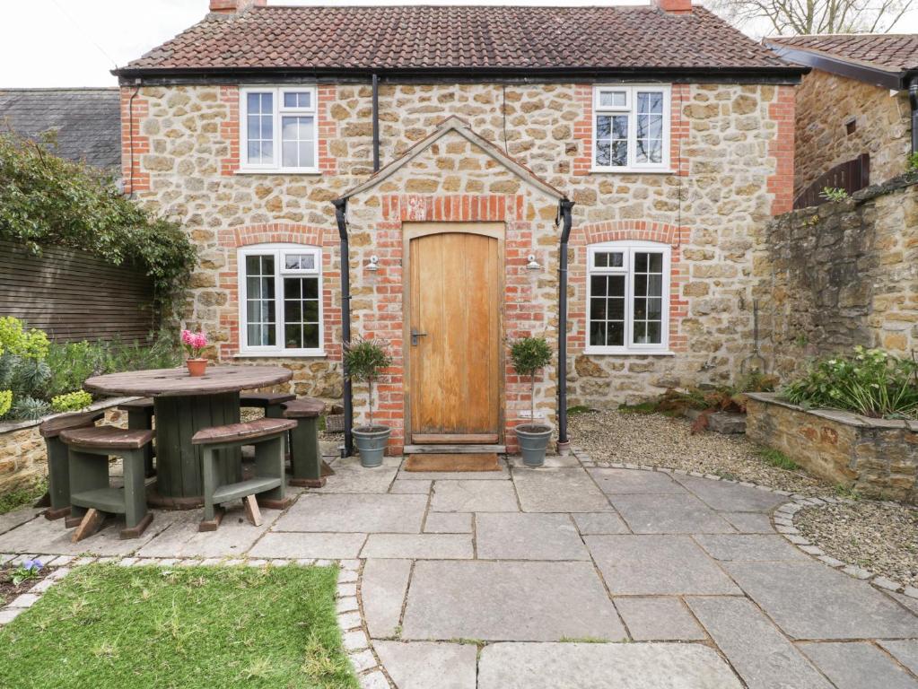 une maison en pierre avec une table et une porte en bois dans l'établissement Bonnings Cottage, à Ilminster