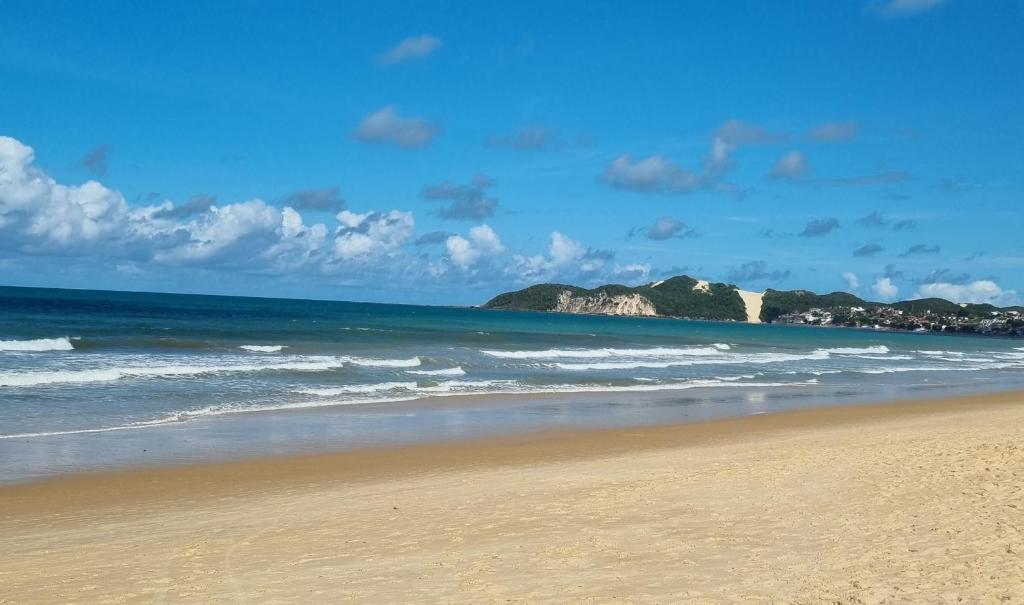 een strand met de oceaan en bergen op de achtergrond bij Flat da Praia Natal in Natal