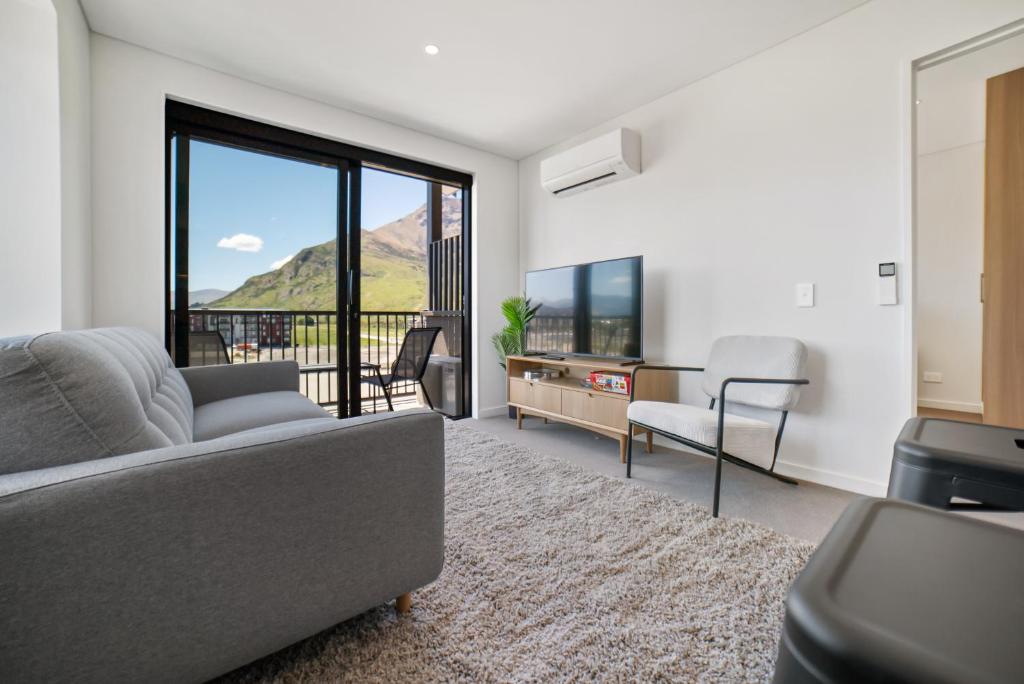 a living room with a couch and a tv at Toru Top Floor Apartment - Brand New & Convenient in Queenstown