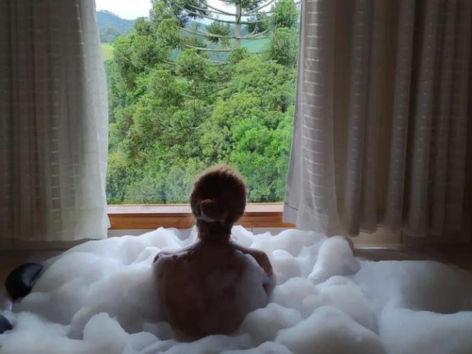 a man sitting in a bed made out of cotton balls at Chalés Cantinho do Céu in Monte Verde