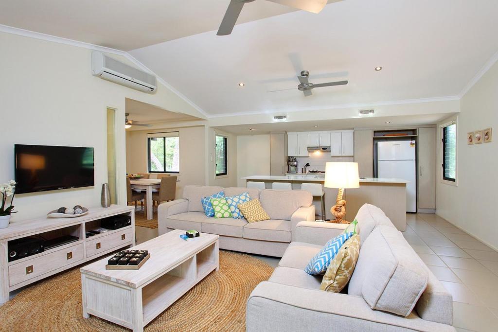 a living room with couches and a flat screen tv at 6 Orania Court Rainbow Shores in Rainbow Beach