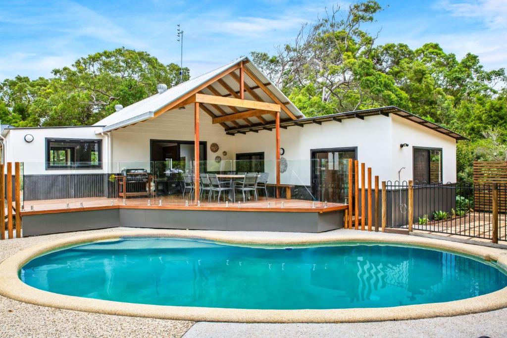 a home with a swimming pool in front of a house at 11 Naiad Court Rainbow Shores in Rainbow Beach