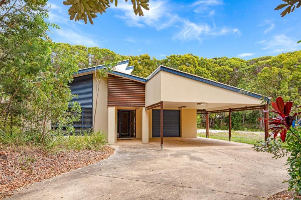 a house with a garage with a driveway at 18 Naiad Court Rainbow Shores in Rainbow Beach