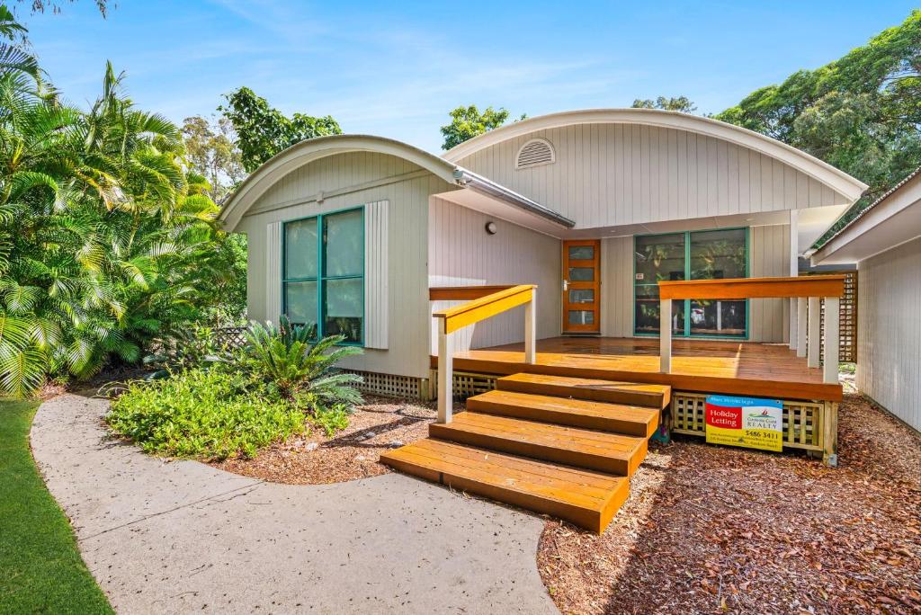 a house with a wooden porch and stairs in front of it at 7 Belle Court Rainbow Shores Fully ducted aircon. Pets welcome in Rainbow Beach