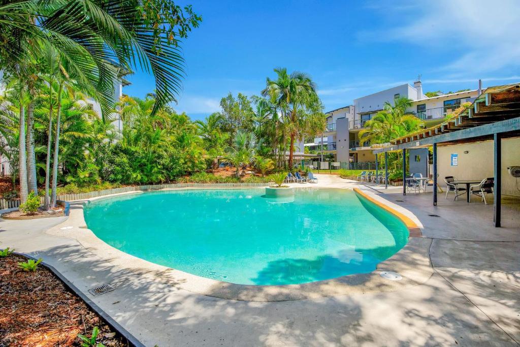 a swimming pool in a resort with palm trees at Baden 52 Rainbow Shores in Rainbow Beach