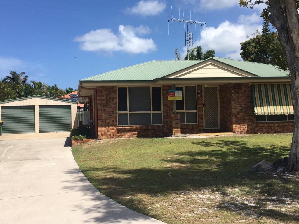 a brick house with a green roof and a driveway at 4 Boronia Place Rainbow Beach in Rainbow Beach