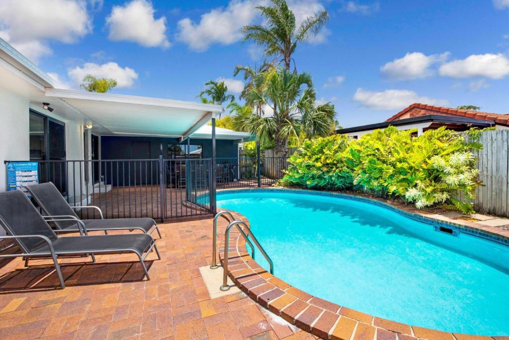 a swimming pool with chairs and a house at Sunyata Beach House Rainbow Beach in Rainbow Beach