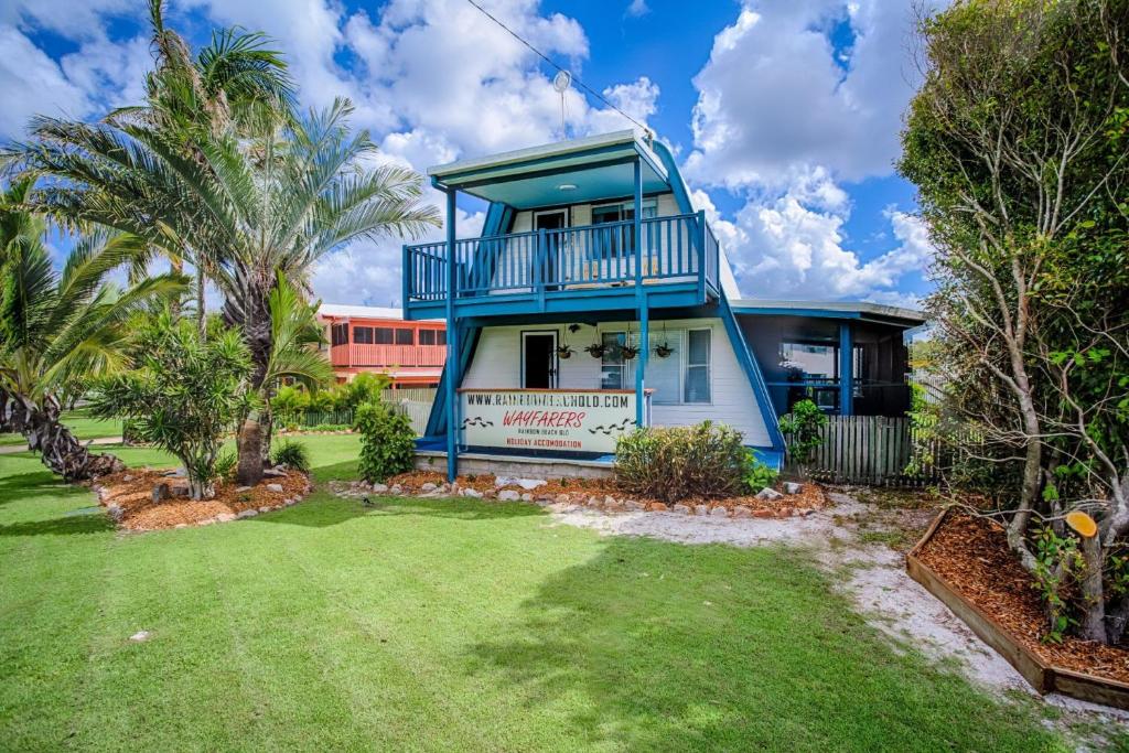 a blue and white house with a yard at Wayfarers Beachouse Rainbow Beach in Rainbow Beach