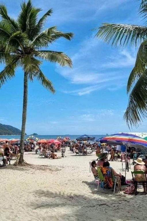 a group of people sitting on a beach with umbrellas at Maydã in Praia Grande
