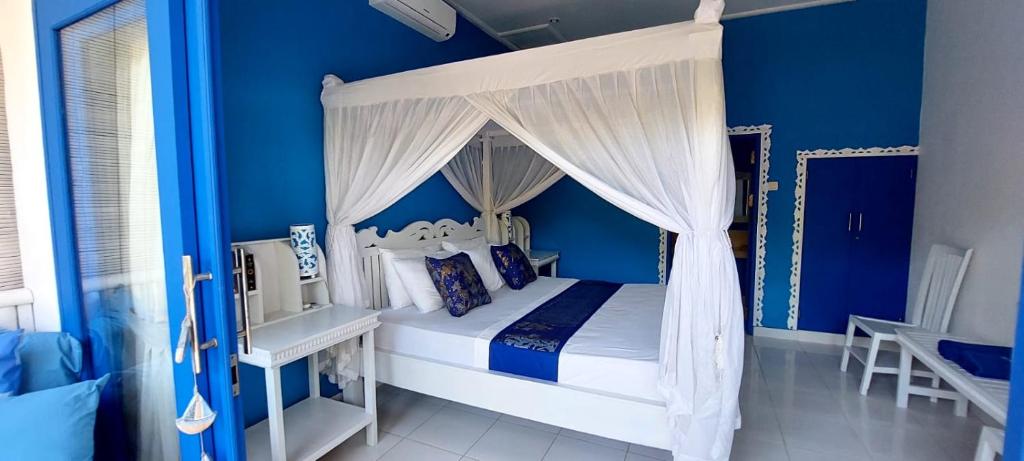 1 dormitorio con cama con dosel y paredes azules en The Shooting Star Homestay, en Amed