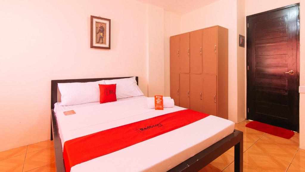 1 dormitorio pequeño con 1 cama con manta roja en RedDoorz @ FDB Homes Nueva Ecija, en Maria Aurora