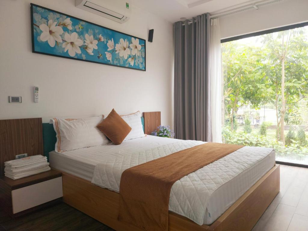 Sun Blush Villas & Resort Hòa Bình في Hòa Bình: غرفة نوم بسرير ونافذة كبيرة
