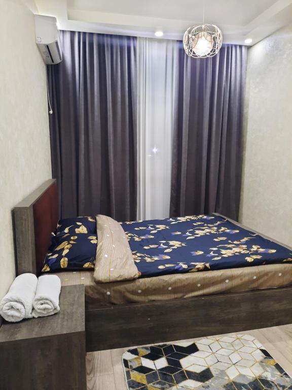 a bedroom with a bed with a blue comforter at 1home in Rustavi