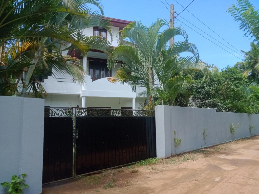 a house with a black gate and palm trees at Silence Paradise in Tangalle