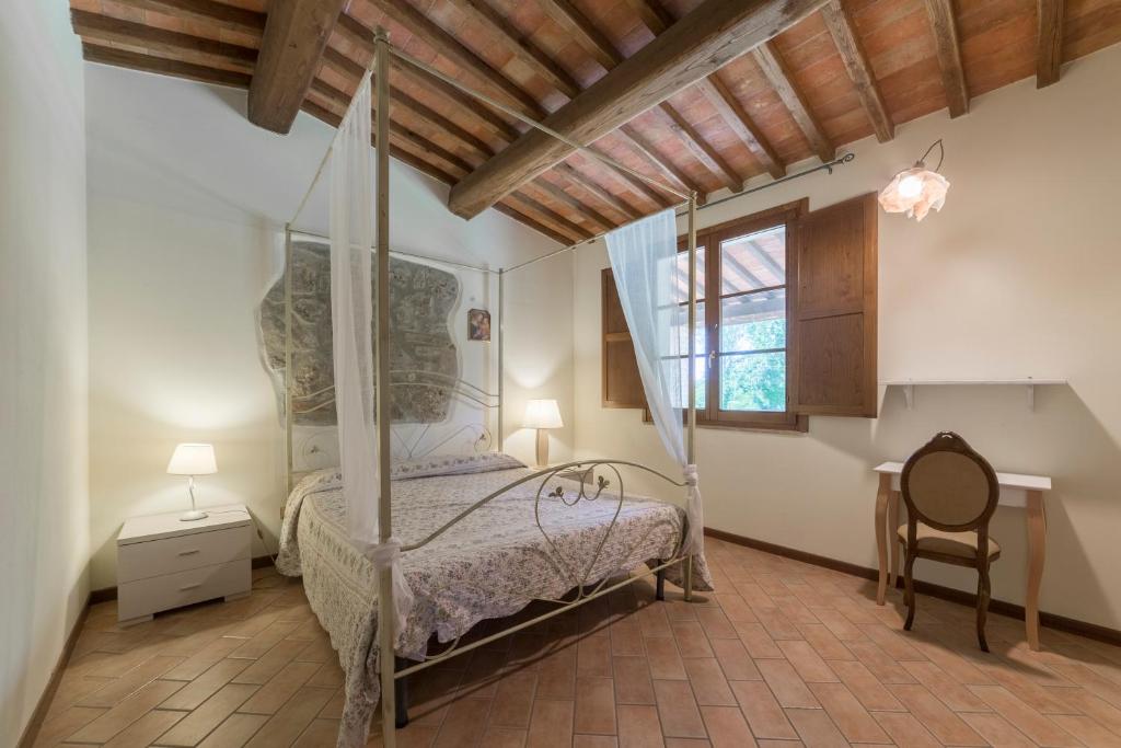 a bedroom with a bed and a desk and a window at Borgo da Vinci in Volterra