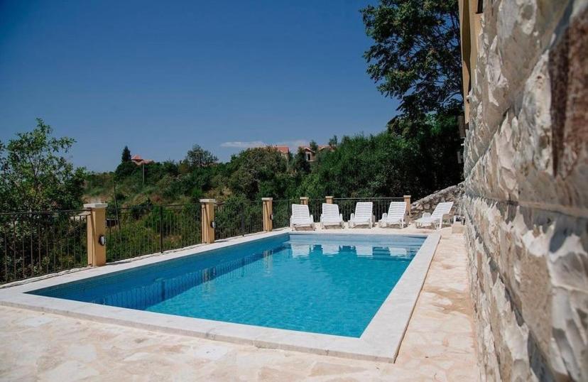 - une piscine avec des chaises blanches dans l'établissement Apartments Casa Bella, à Kotor