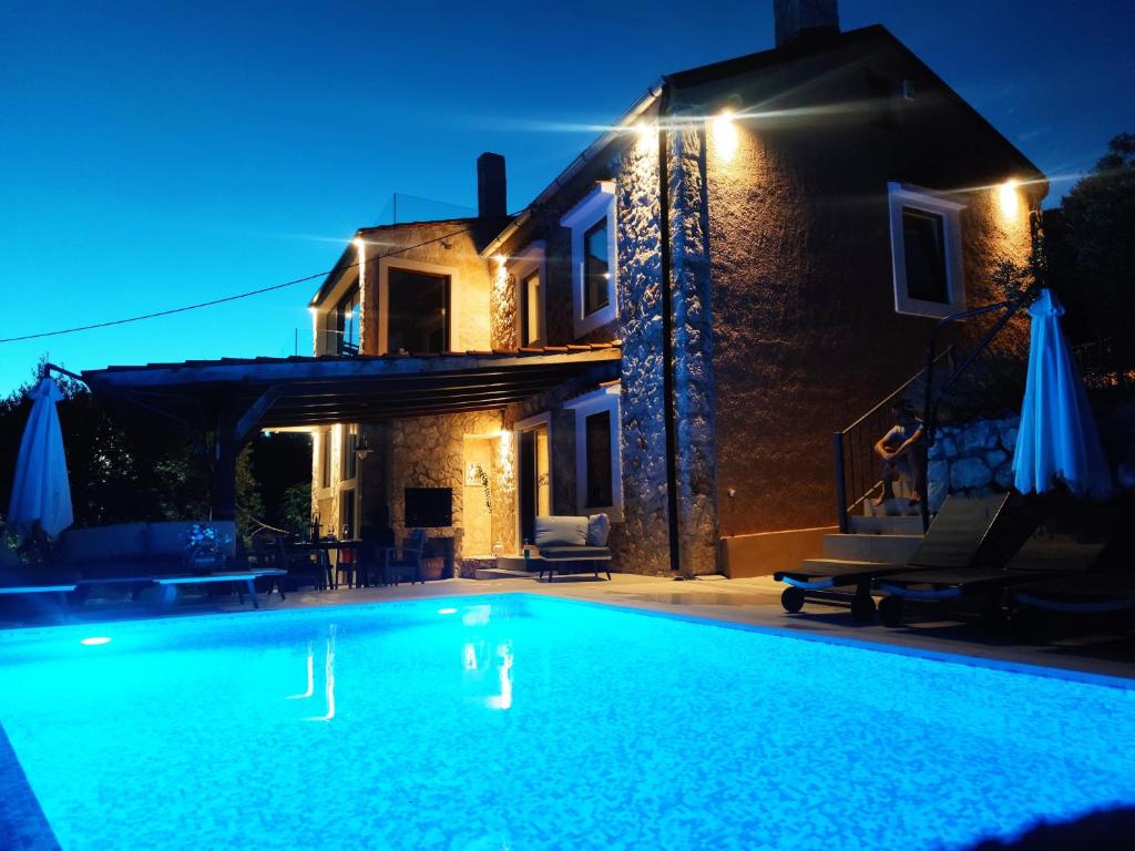 una piscina frente a una casa por la noche en Stone hause Noa en Rab