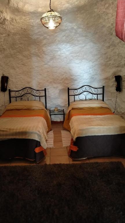 sypialnia z 2 łóżkami i żyrandolem w obiekcie Casa Cueva Sierra Nevada - Monachil w mieście Monachil