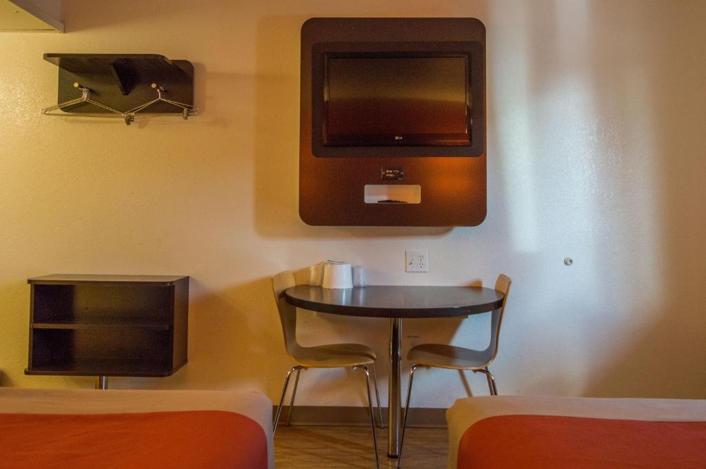 a room with a table and a tv on the wall at Motel 6-Ardmore, OK in Ardmore