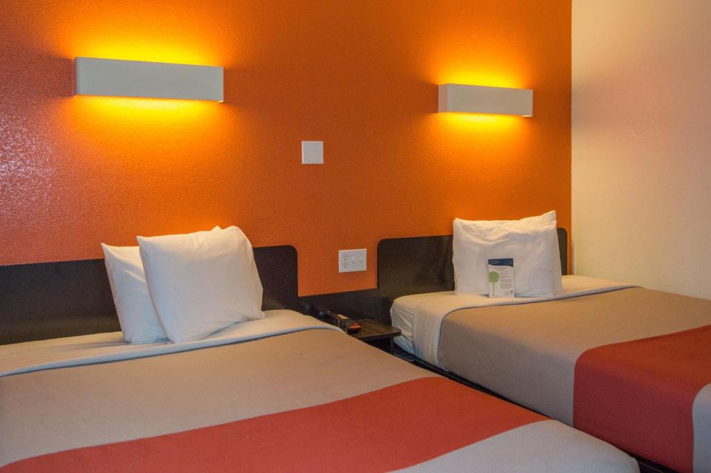 two beds in a hotel room with orange walls at Motel 6-Ardmore, OK in Ardmore