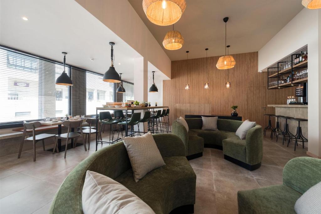 una sala de estar con sofás verdes y un bar en Oliva Welcoming Apartments, en Proença-a-Nova