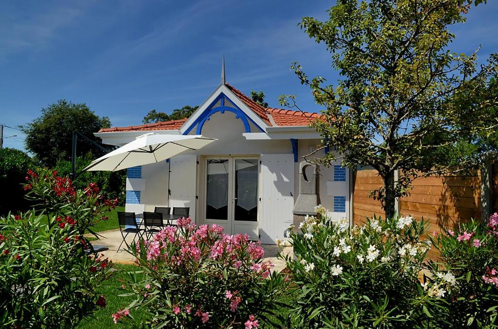 una pequeña casa con sombrilla y algunas flores en Dousoleil, en La Teste-de-Buch