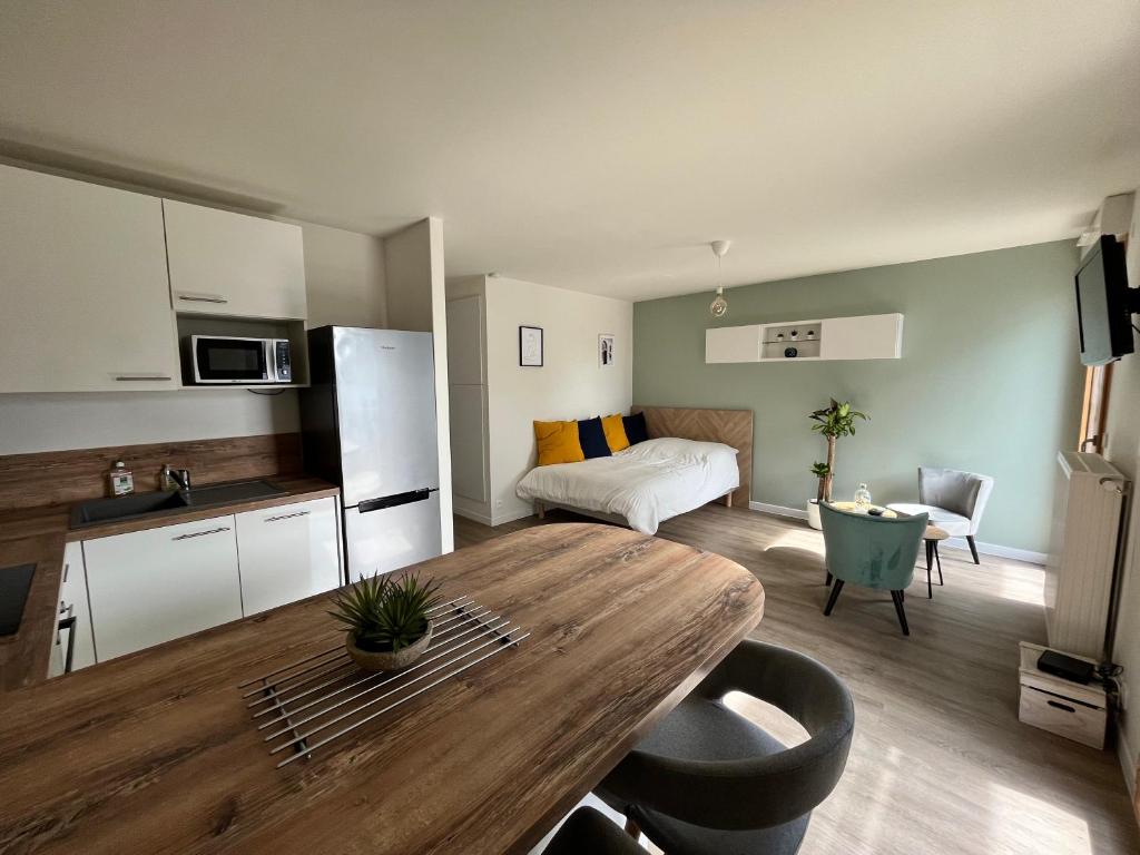 cocina y sala de estar con mesa de madera en una habitación en Studio Cosy et son Emplacement Idéal en Montévrain